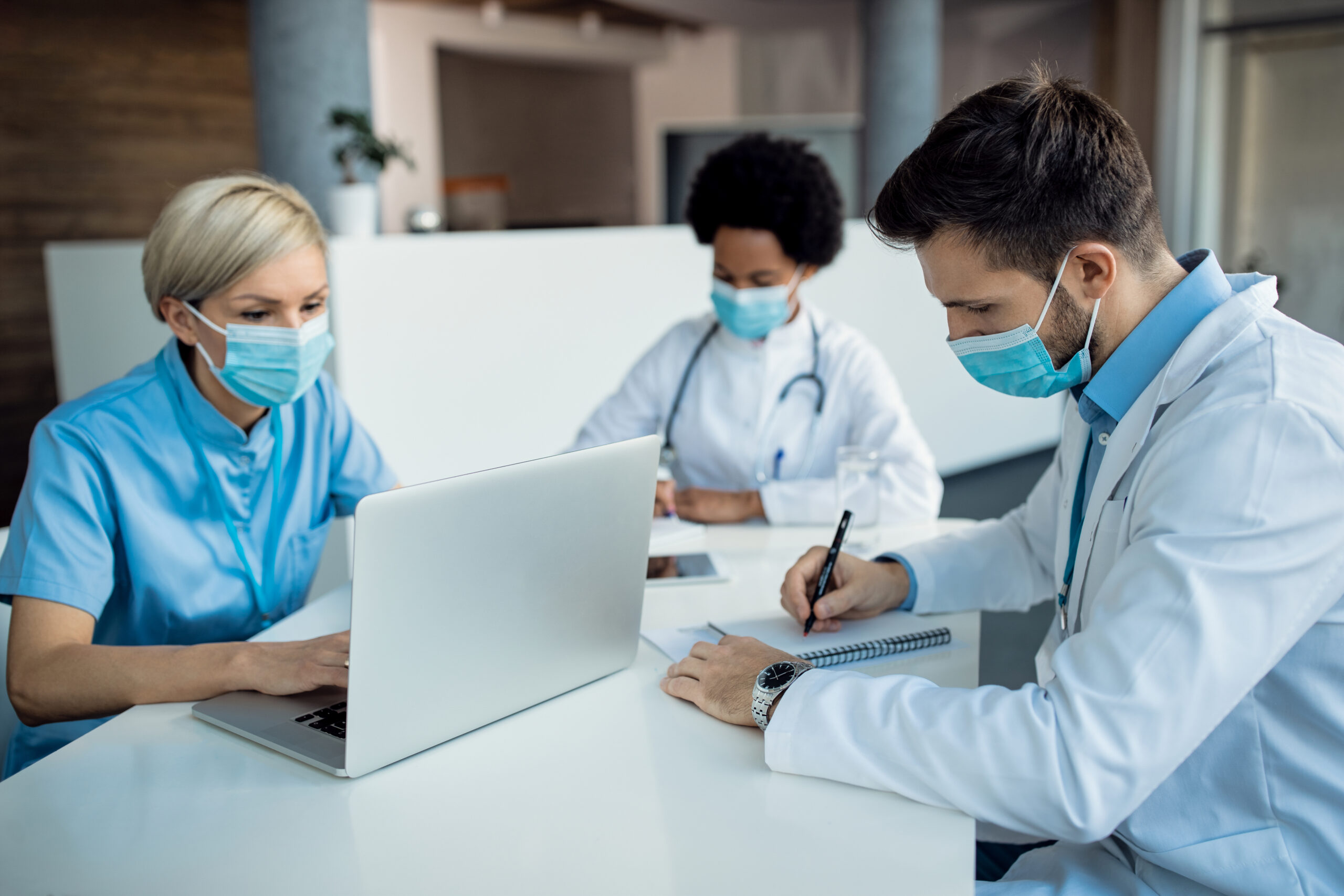 Male doctor taking notes while working with colleagues at medica